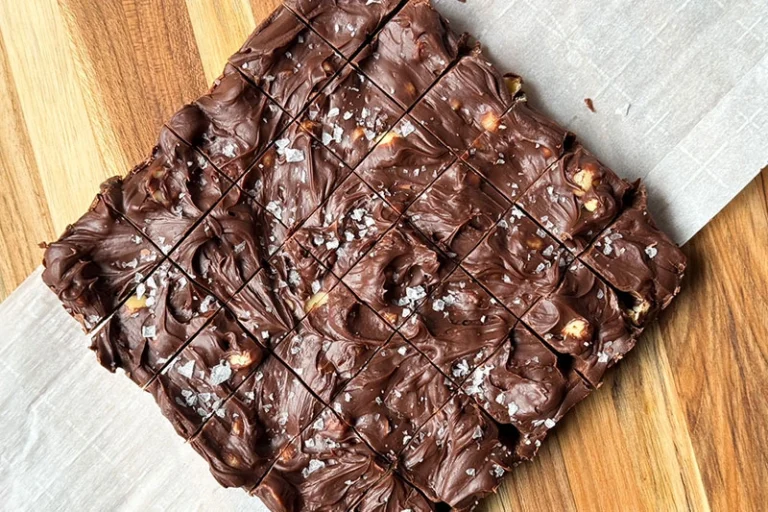 cut dark chocolate macadamia nut fudge on a cutting board.