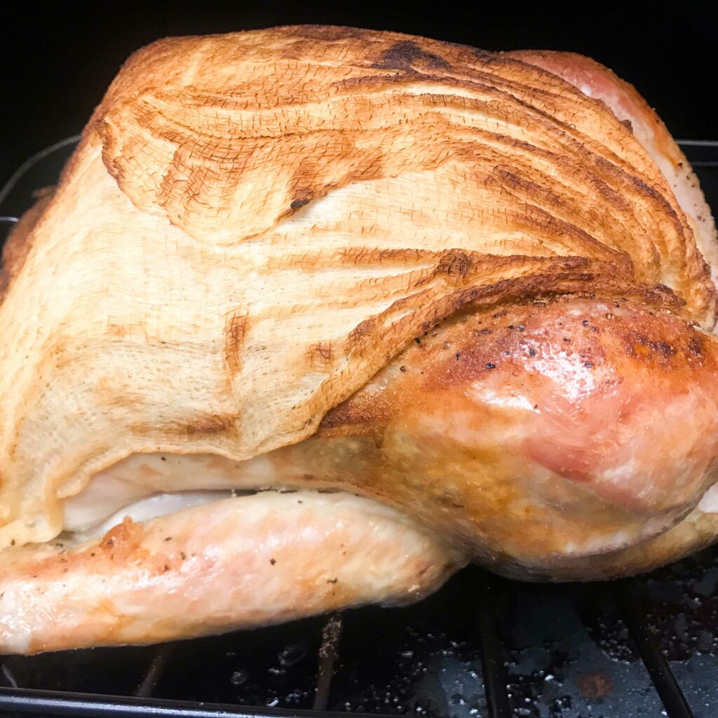 two hours of cooked turkey with cheesecloth ready to be removed.