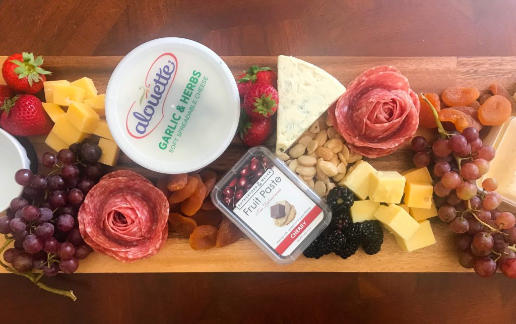 long cheeseboard with cheese, fruit, honey and salami rose