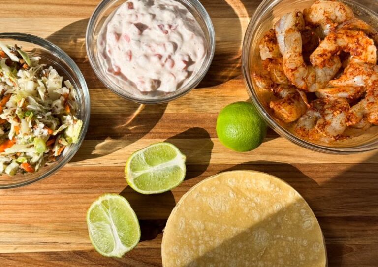 bowl of slaw, bowl of sauce, bowl of shrimp, tortillas and limes.