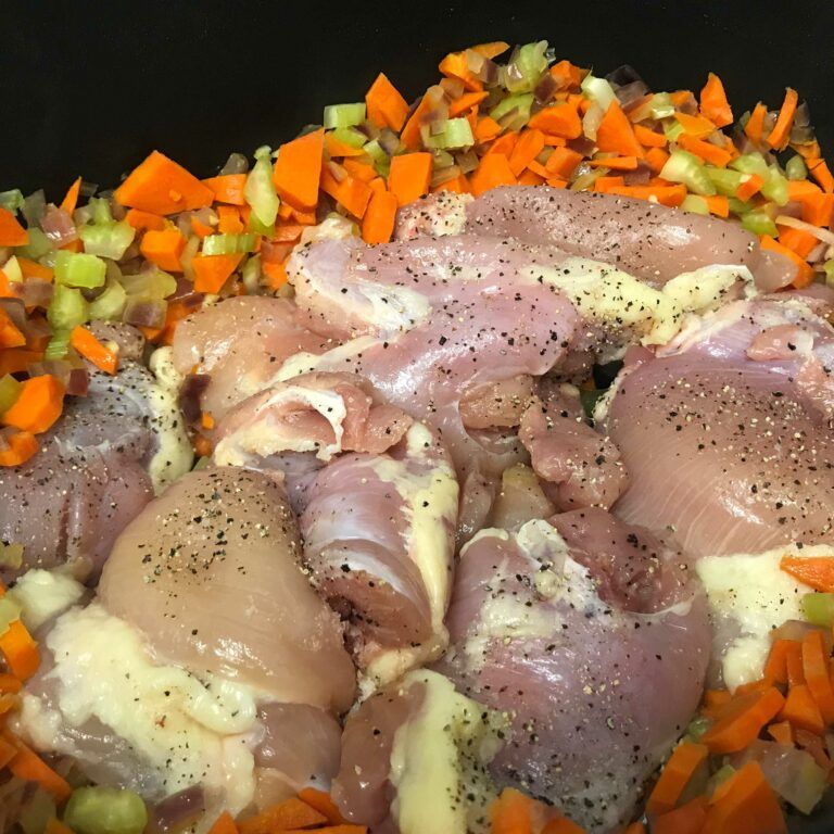 raw chicken nestled in cooked veggies