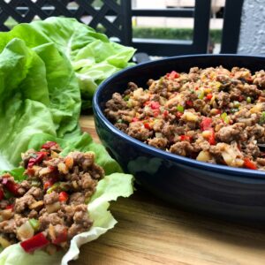 bowl of turkey filling next to lettuce wrap filled with meat.