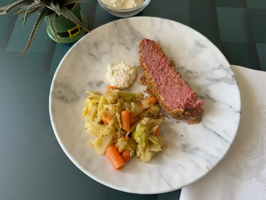 plate of corned beef, sauce and cabbage and carrots.