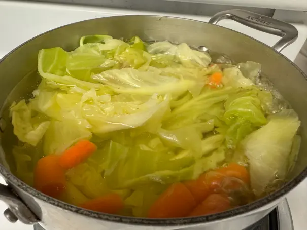 cabbage and carrots cooking in a pot.