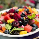 Exotic fruit salad with honey and lime dressing on a platter.