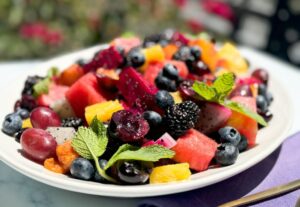 Exotic fruit salad with honey and lime dressing on a platter.