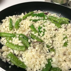 cauliflower, onions and snap peas in a skillet.