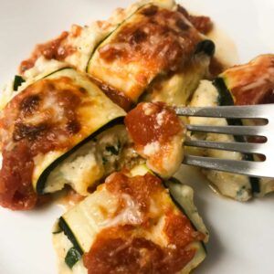 a plate of cooked roll ups with a fork holding a piece