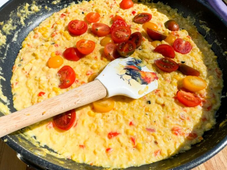 skillet of corn puree with tomatoes.