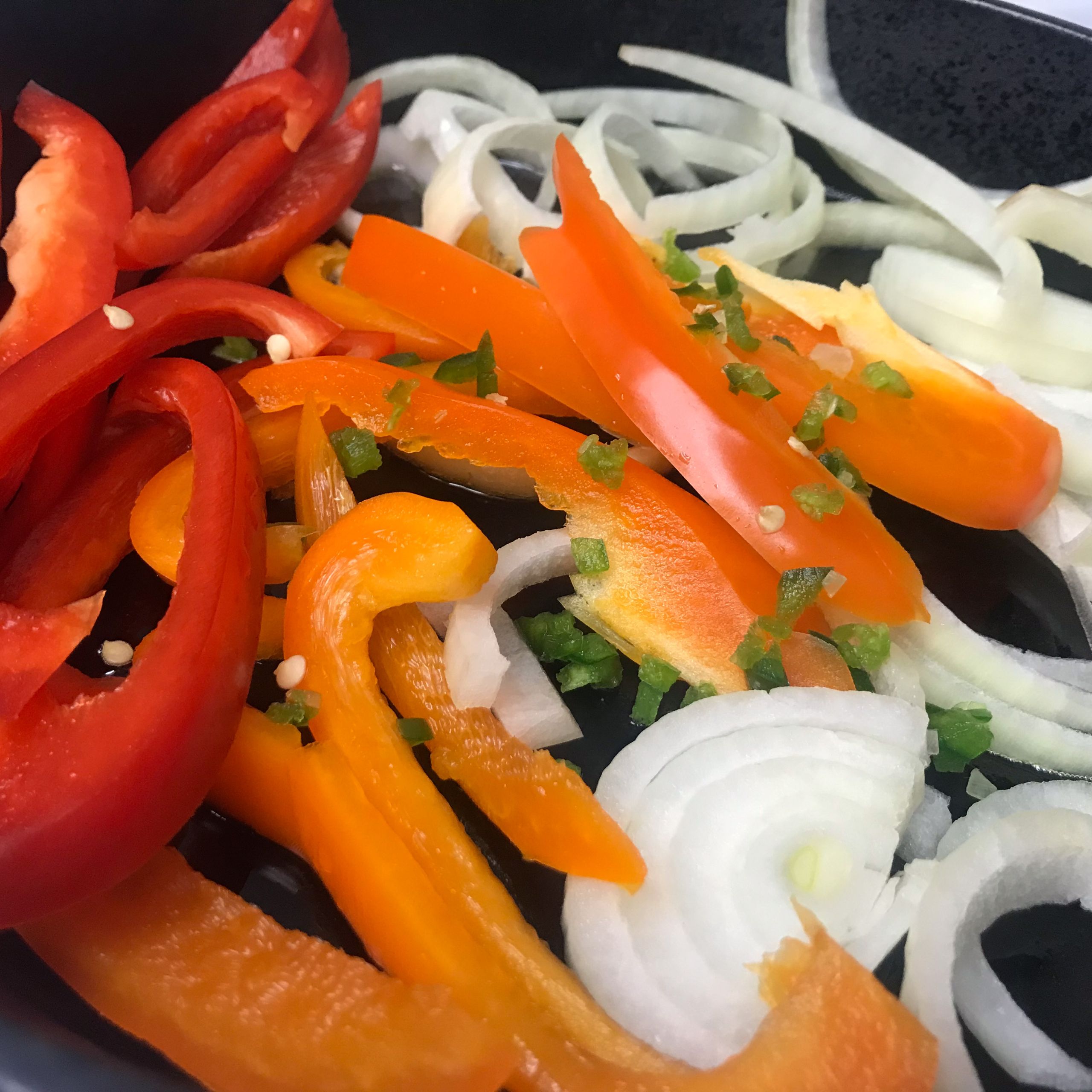 raw peppers and onions in a skillet