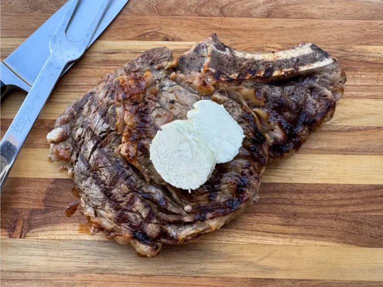 Grilled ribeye steak topped with slices of butter.