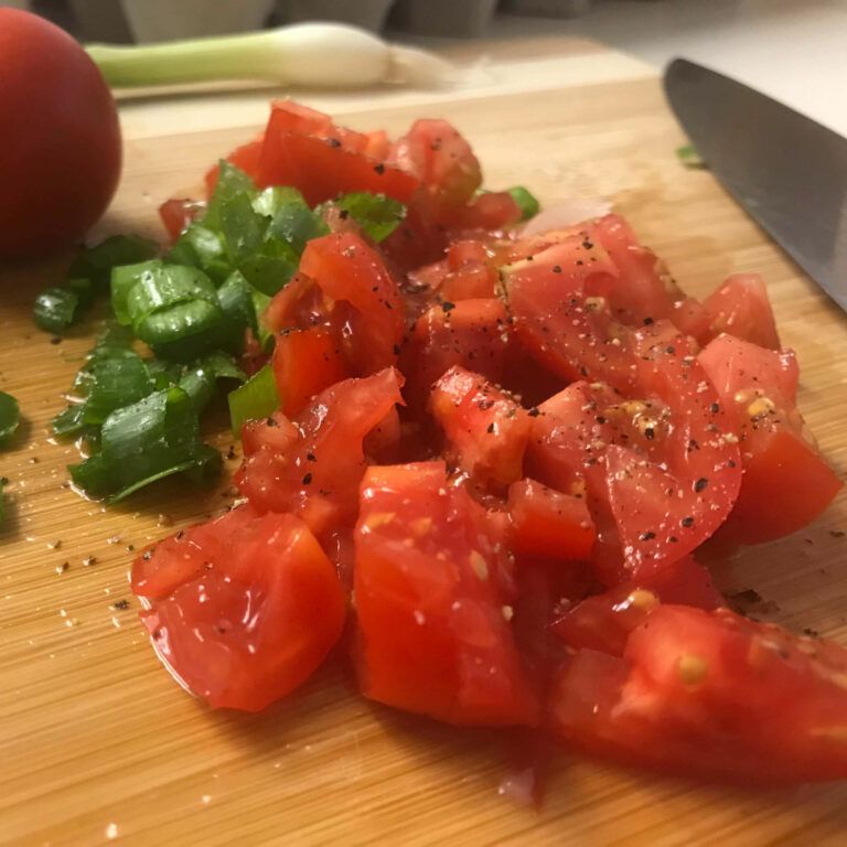 chopped tomatoes and green onion on cutting board