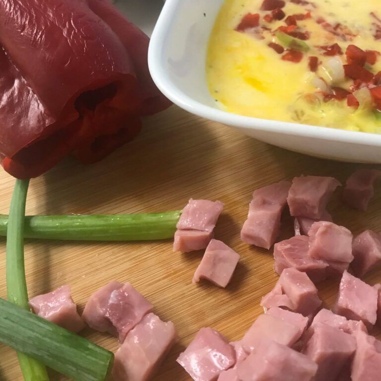 chopped ham on a board next to bowl of mixed eggs and veggies