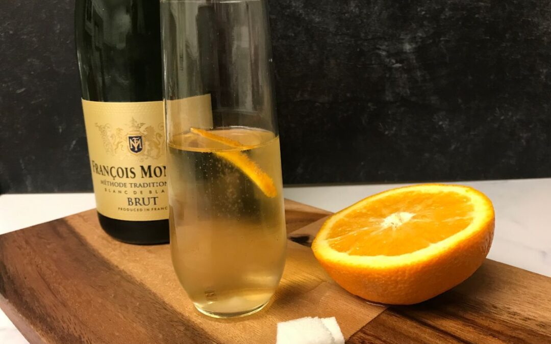 Champagne cocktail with champaign bottle, orange and sugar cubes