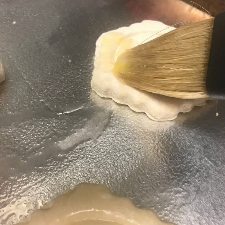 puff pastry cup on baking sheet being brushed with egg wash