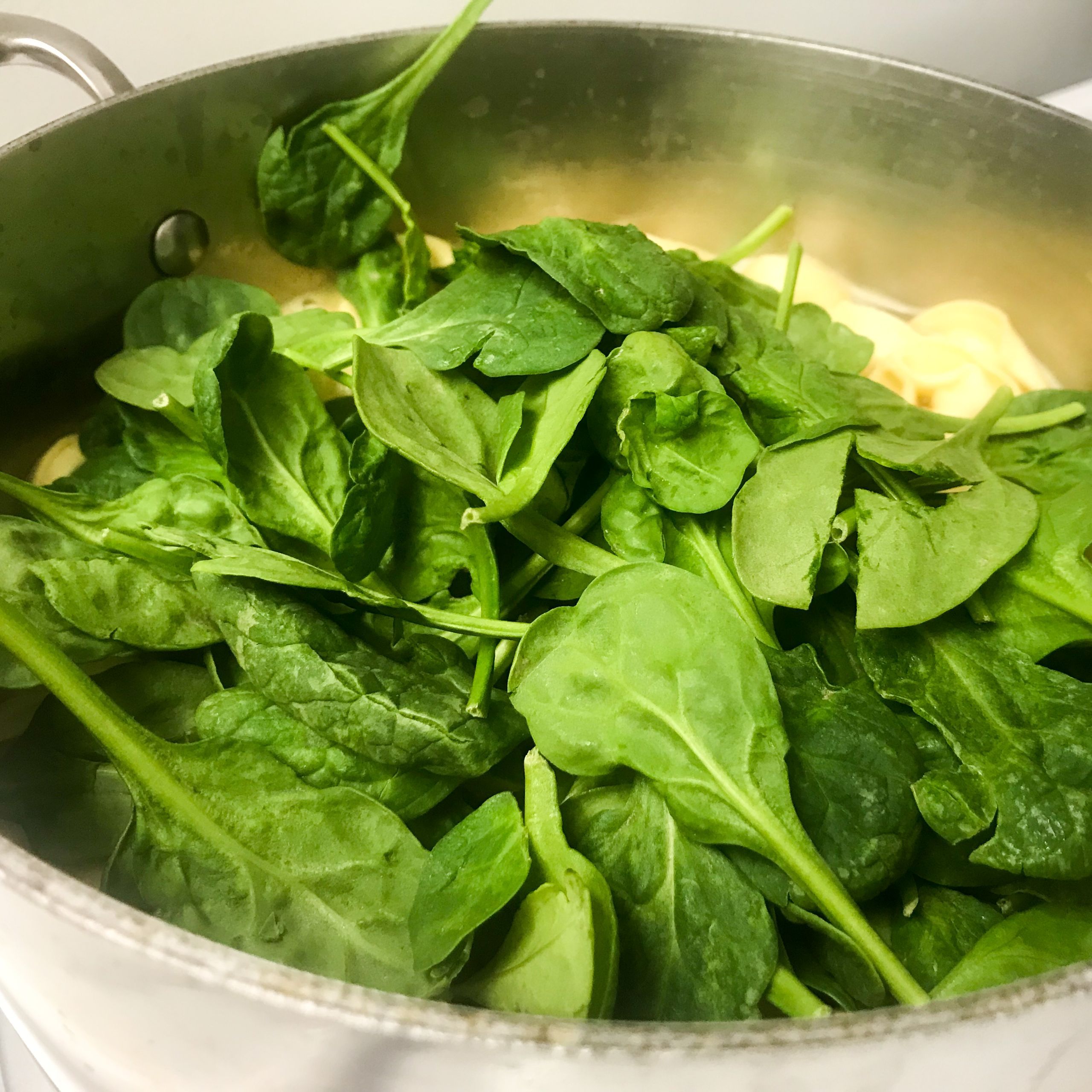 spinach and cheese tortellini cooking in a pot