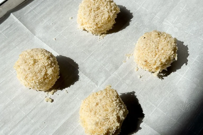 breaded baby brie on a baking sheet.