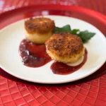 fried baby brie bites with tart cherry jam on a plate.