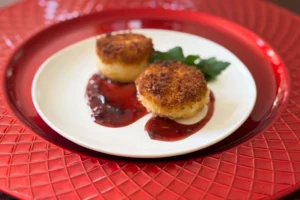 fried baby brie bites with tart cherry jam on a plate.