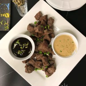 steak filet bites on a platter with dipping sauces.