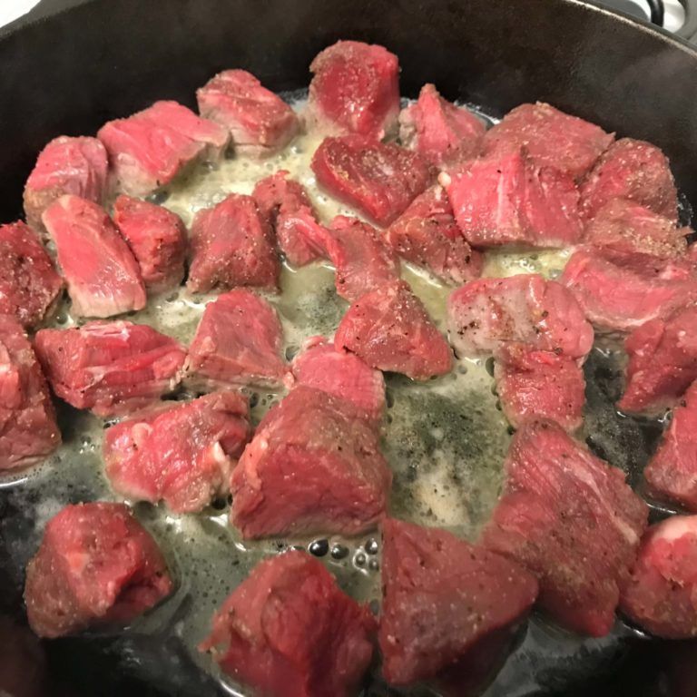 beef bites cooking in skillet.