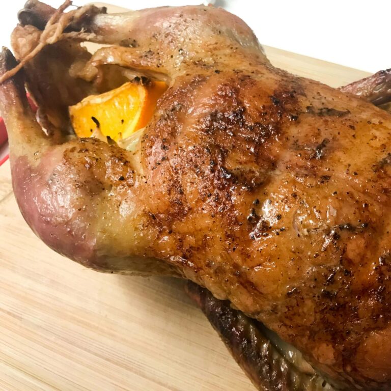 roasted duck resting on cutting board.