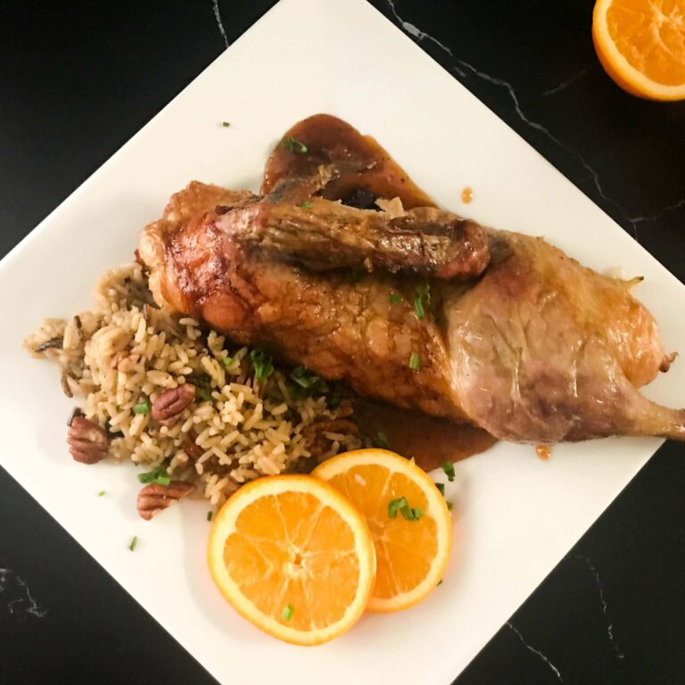 plated half duck with rice pilaf.