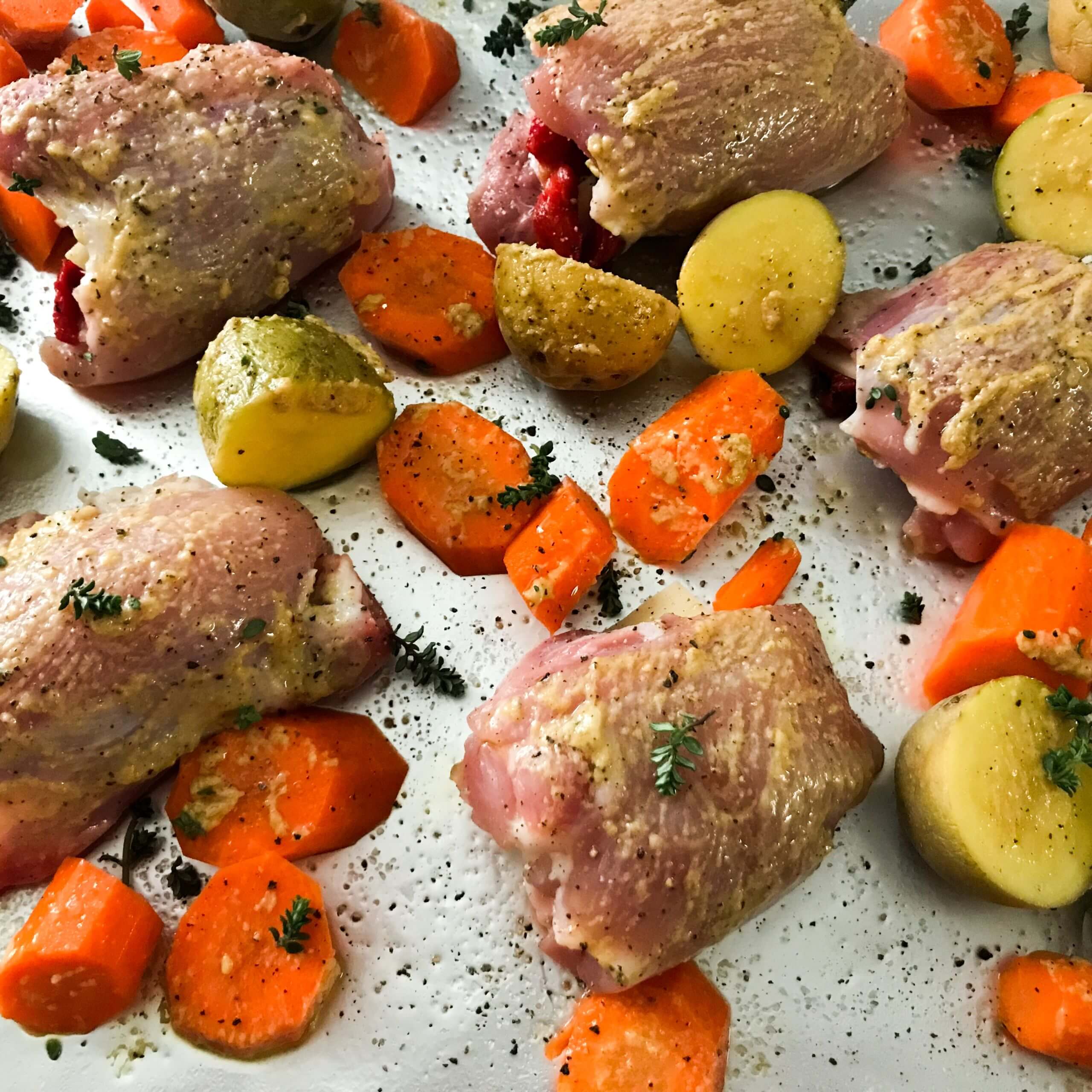 Sheet Pan Stuffed chicken thighs and carrots and potatoes on a tray | My Curated Tastes
