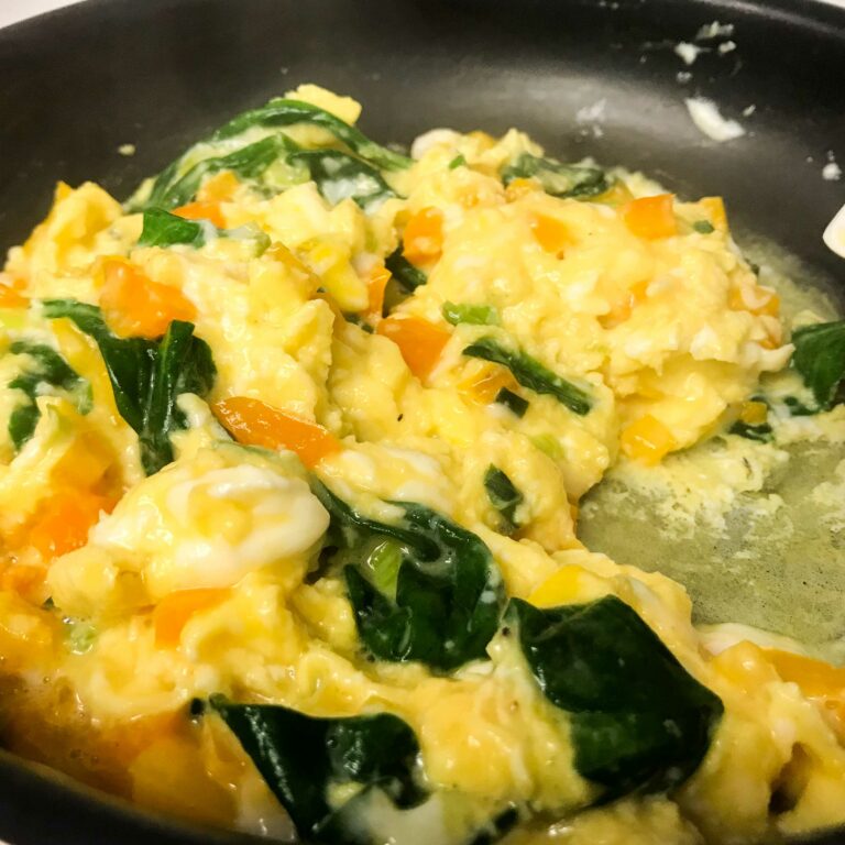 scrambled eggs and veggies in skillet.