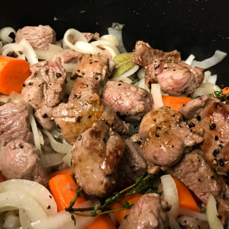 cooked lamb and veggies in pot.
