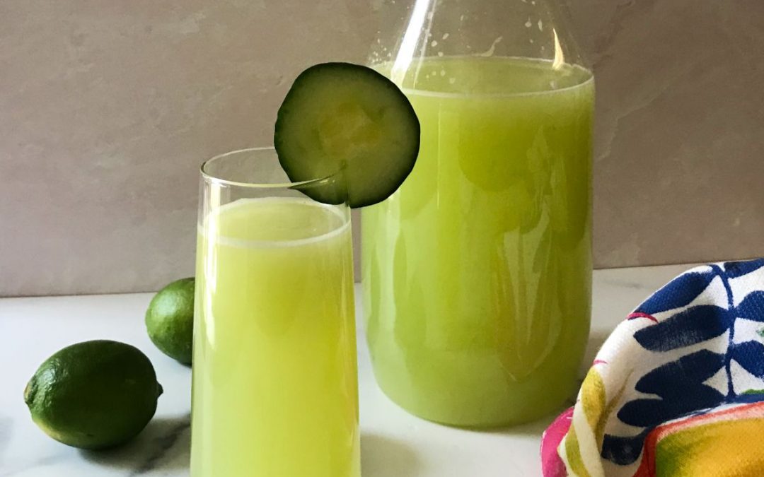 glass of cucumber and lime agua fresca and limes | my curated tastes