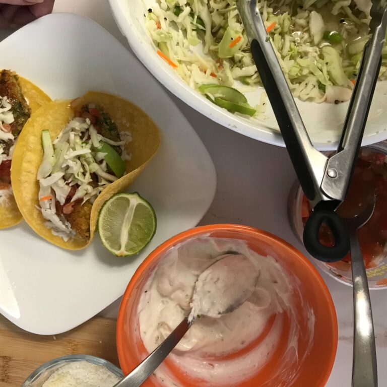 finished tacos with bowls of slaw and crema.