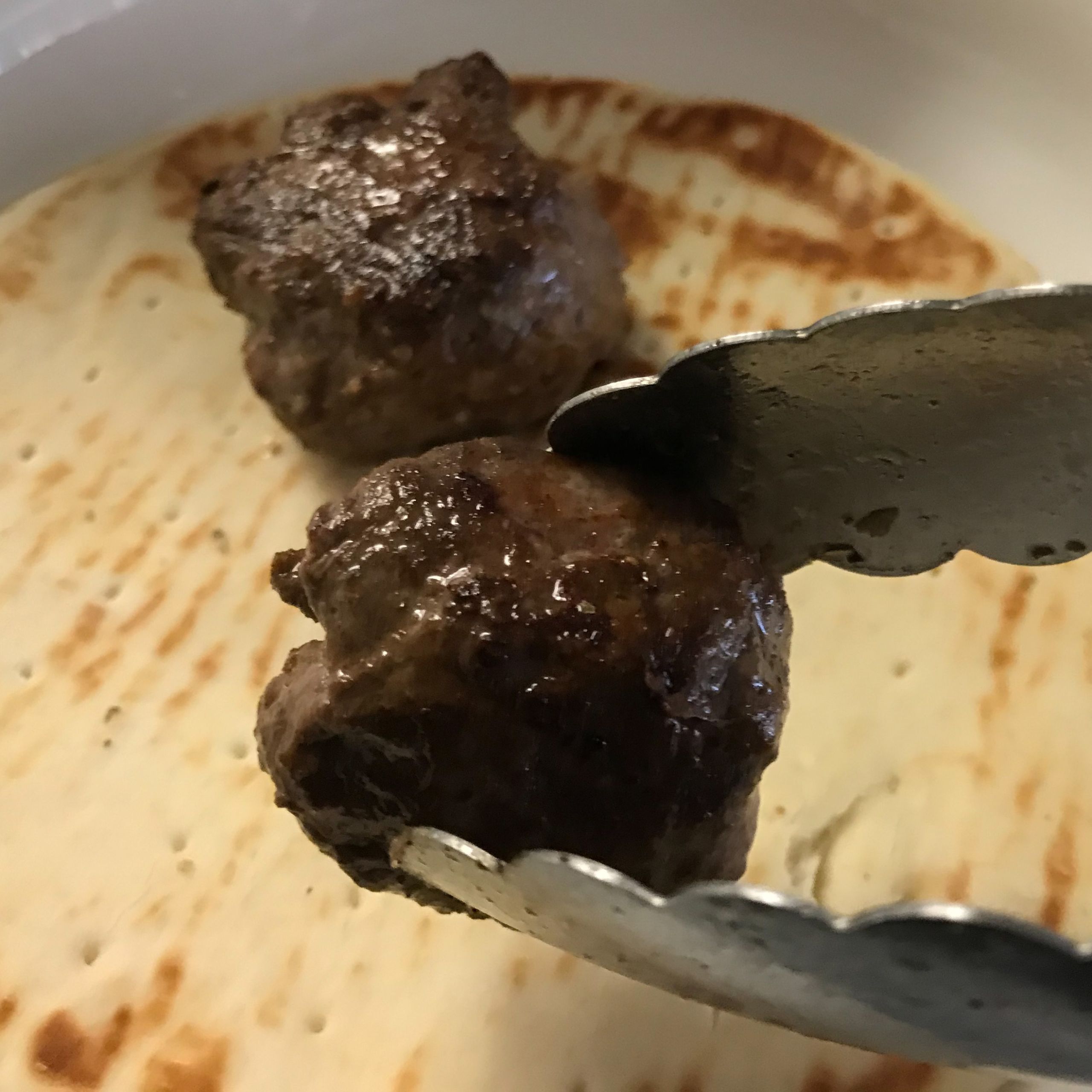 cooked meatballs being put on pita | my curated tastes