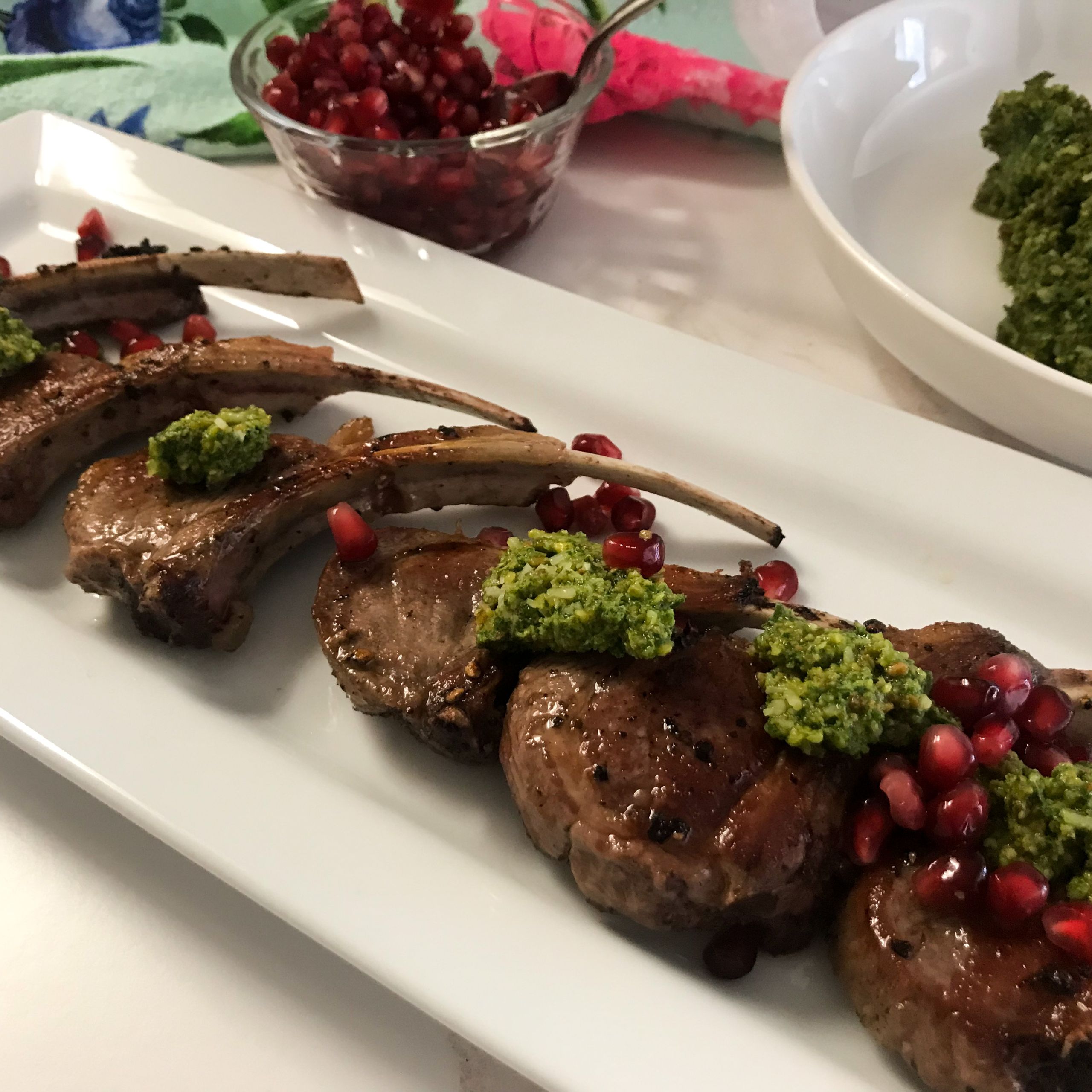 FINISHED LAMB CHOPS TOPPED WITH PESTO AND POMEGRANATE SEEDS ON PLATTER | MY CURATED TASTES