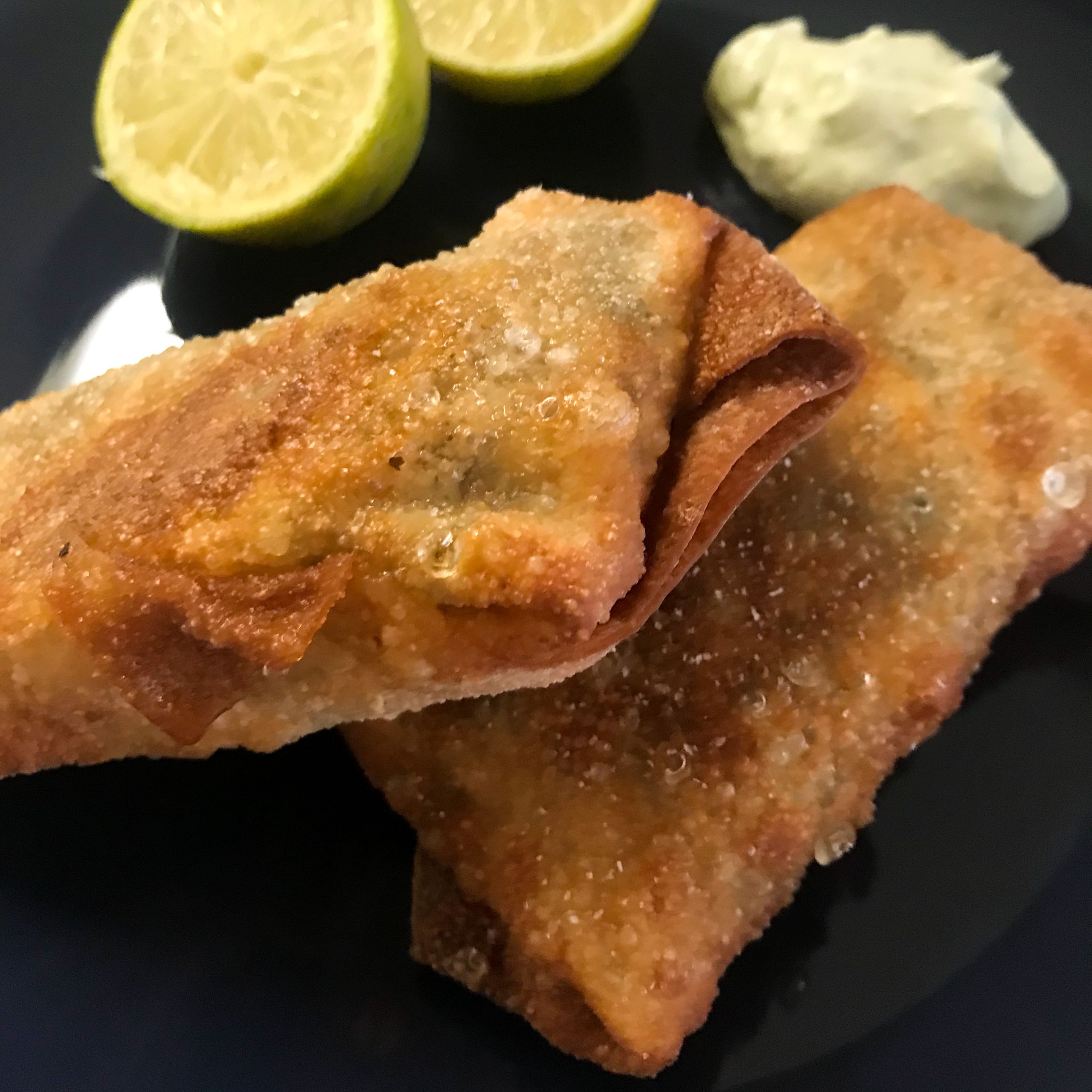 Cooked Southwest Egg rolls on plate with lime avocado crema and cut limes | my curated tastes