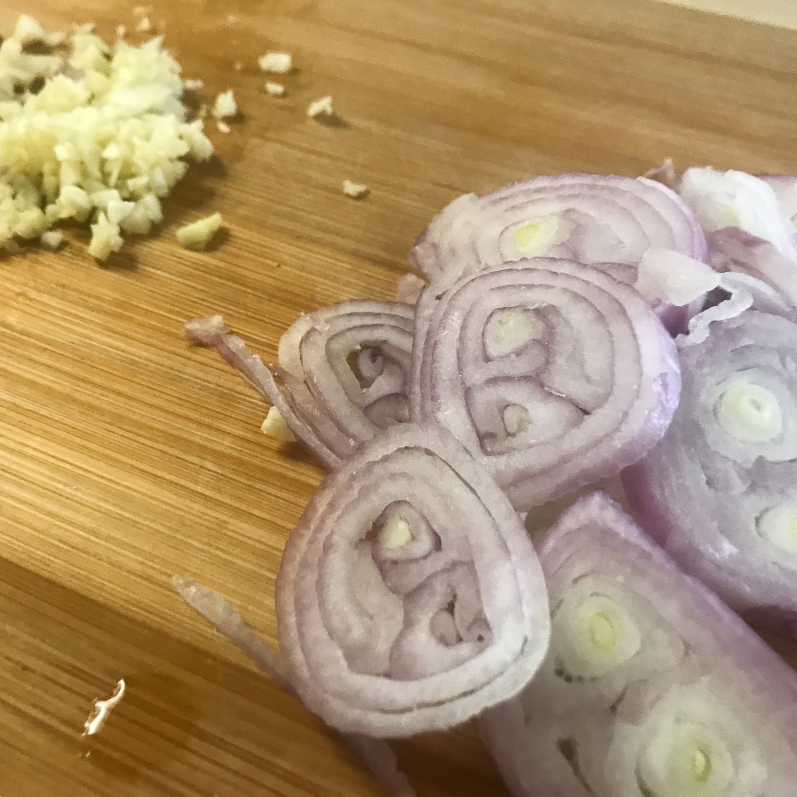 chopped garlic and sliced shallots on a cutting board