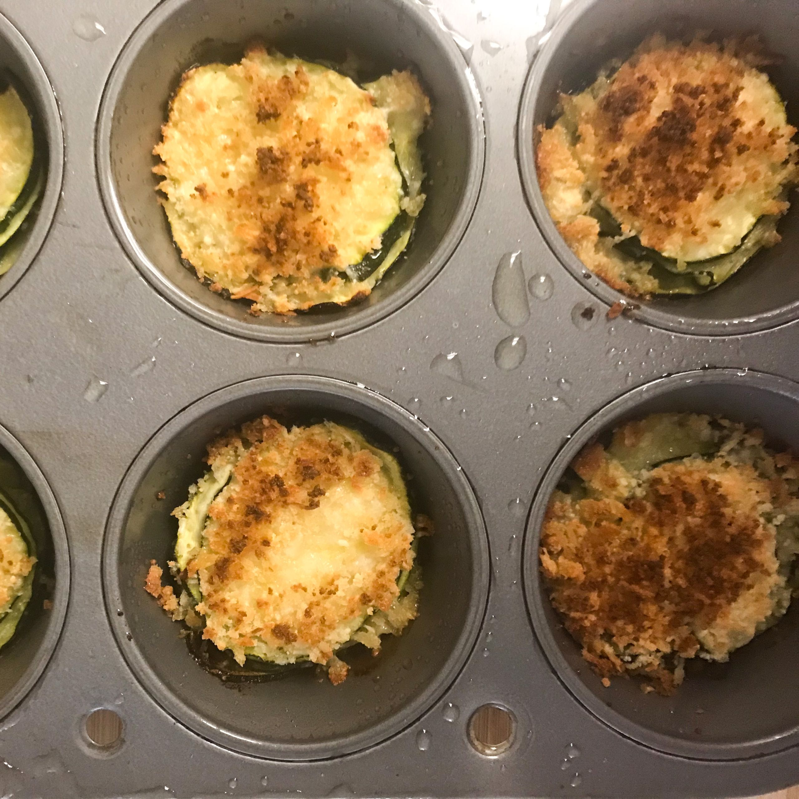 cooked zucchini stacks in muffin tin right out of oven