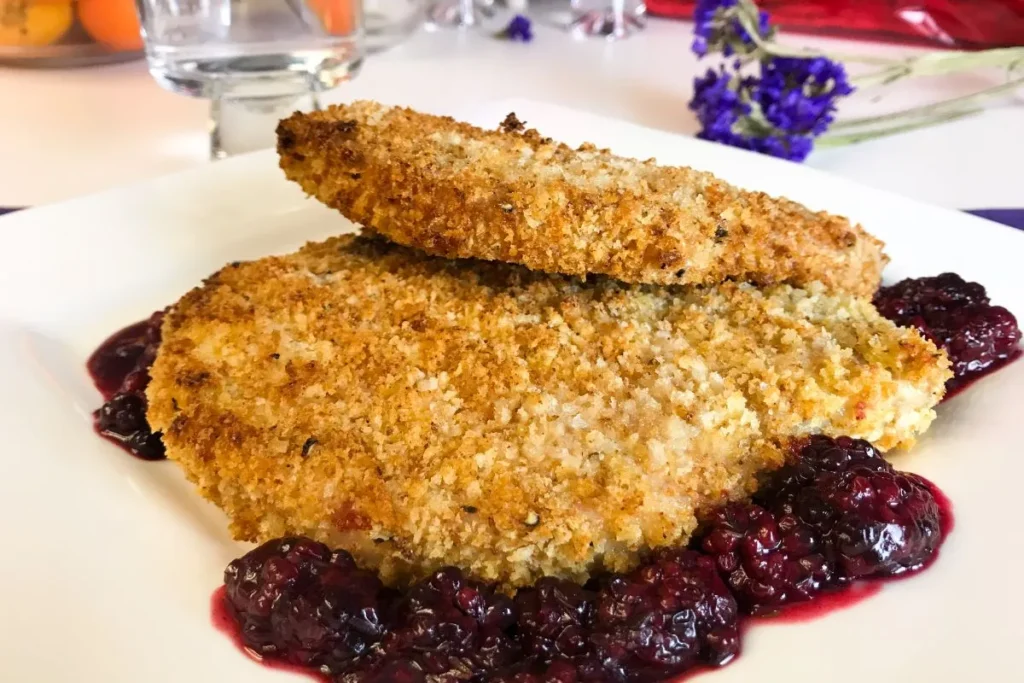 breaded baked pork chops on top of blackberry sauce.