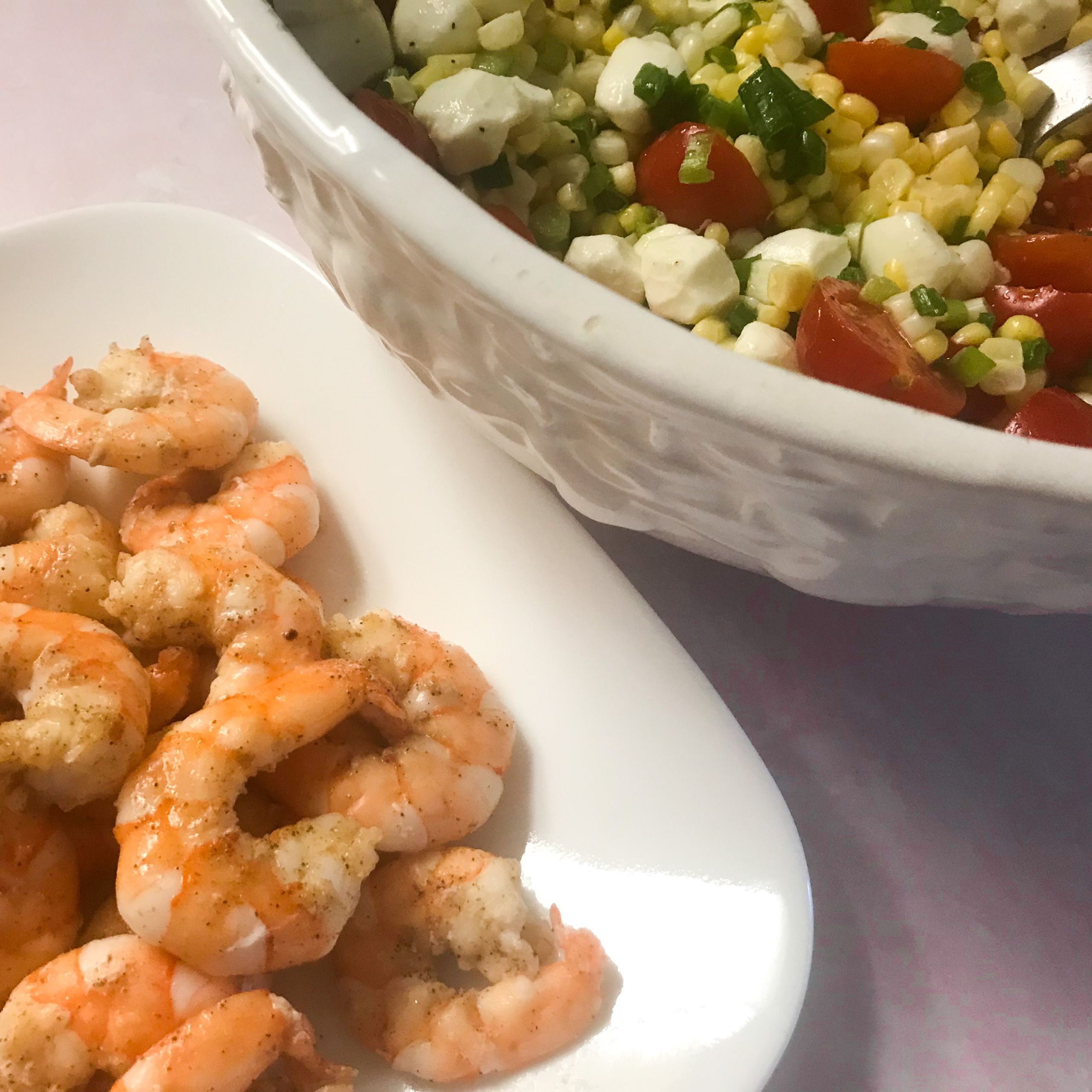 cooked shrimp on a plate with bowl of veggies