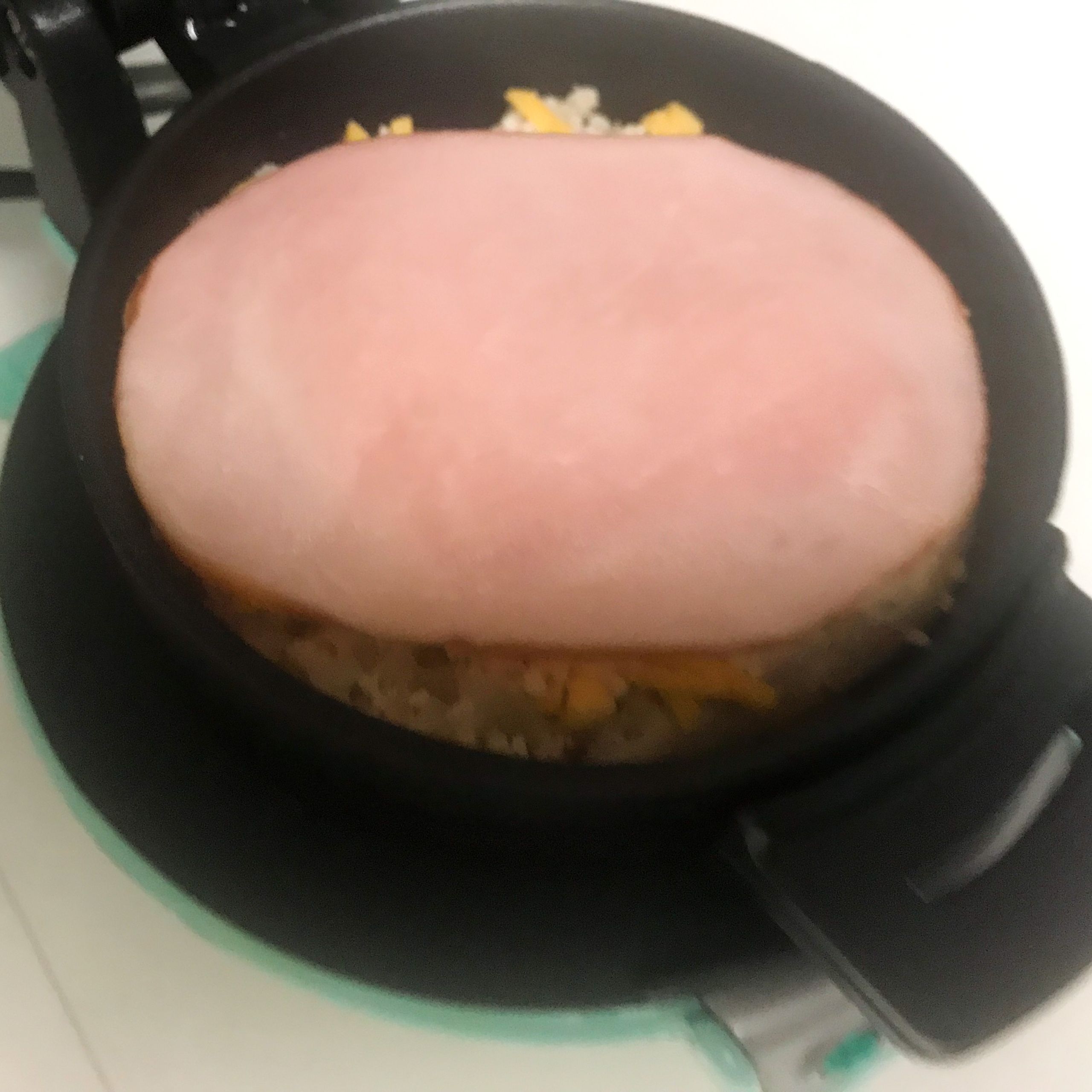 bottom half of english muffin, cheeses and ham in breakfast sandwich maker