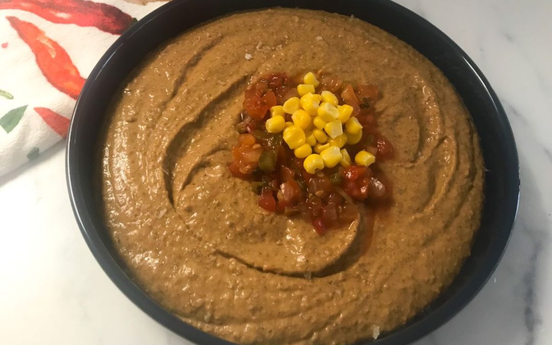 three bean hummus in a bowl topped with salsa and corn