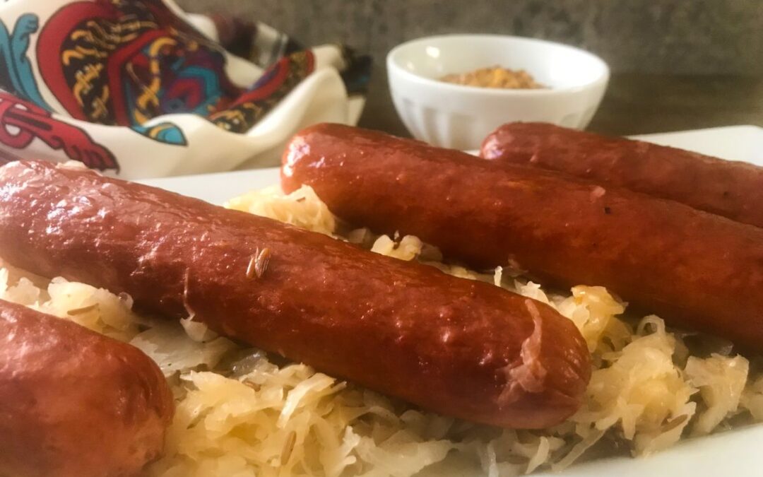 KNOCKWURST AND SAUERKRAUT ON A PLATTER WITH A BOWL OF MUSTARD