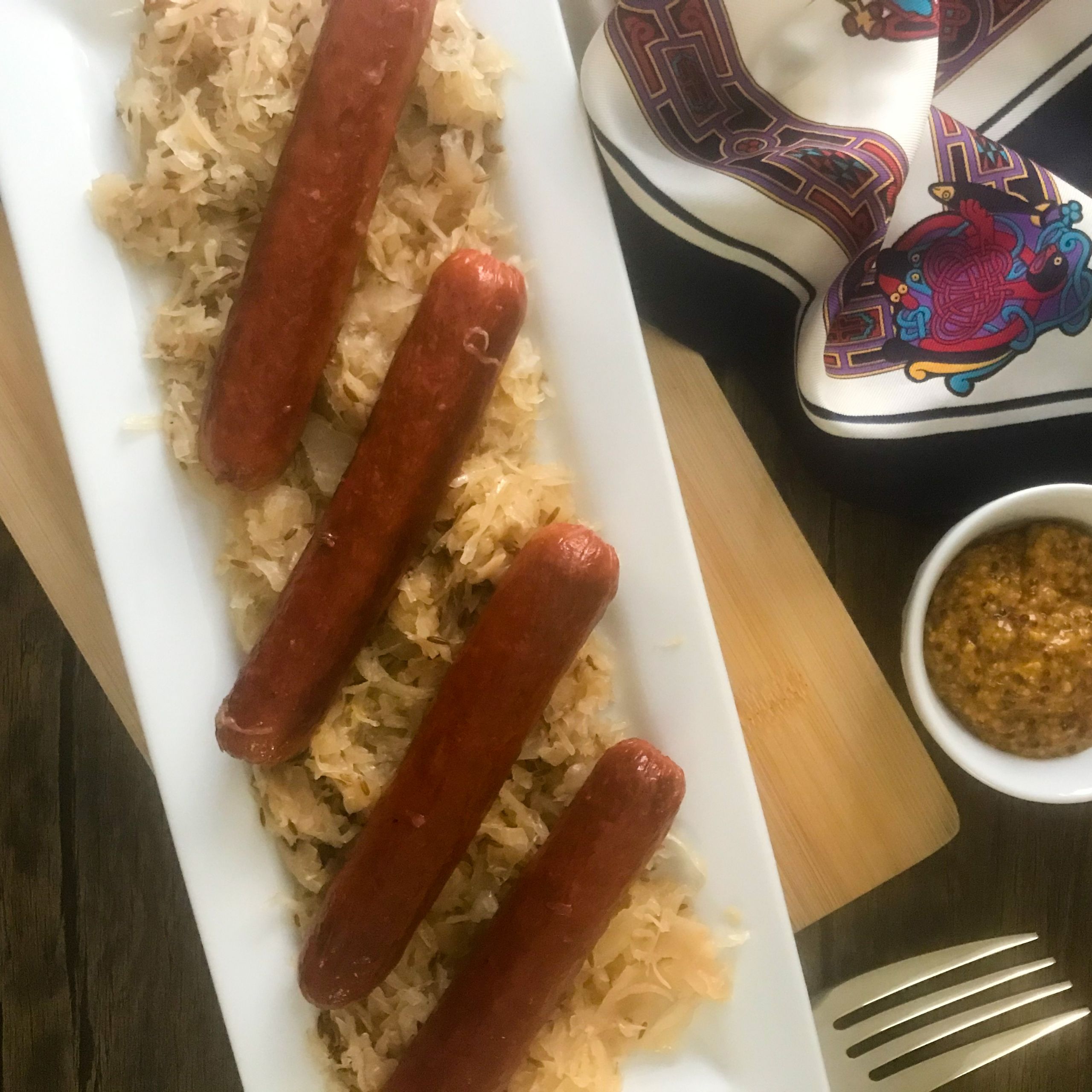knockwurst and sauerkraut on a platter with a bowl of mustard
