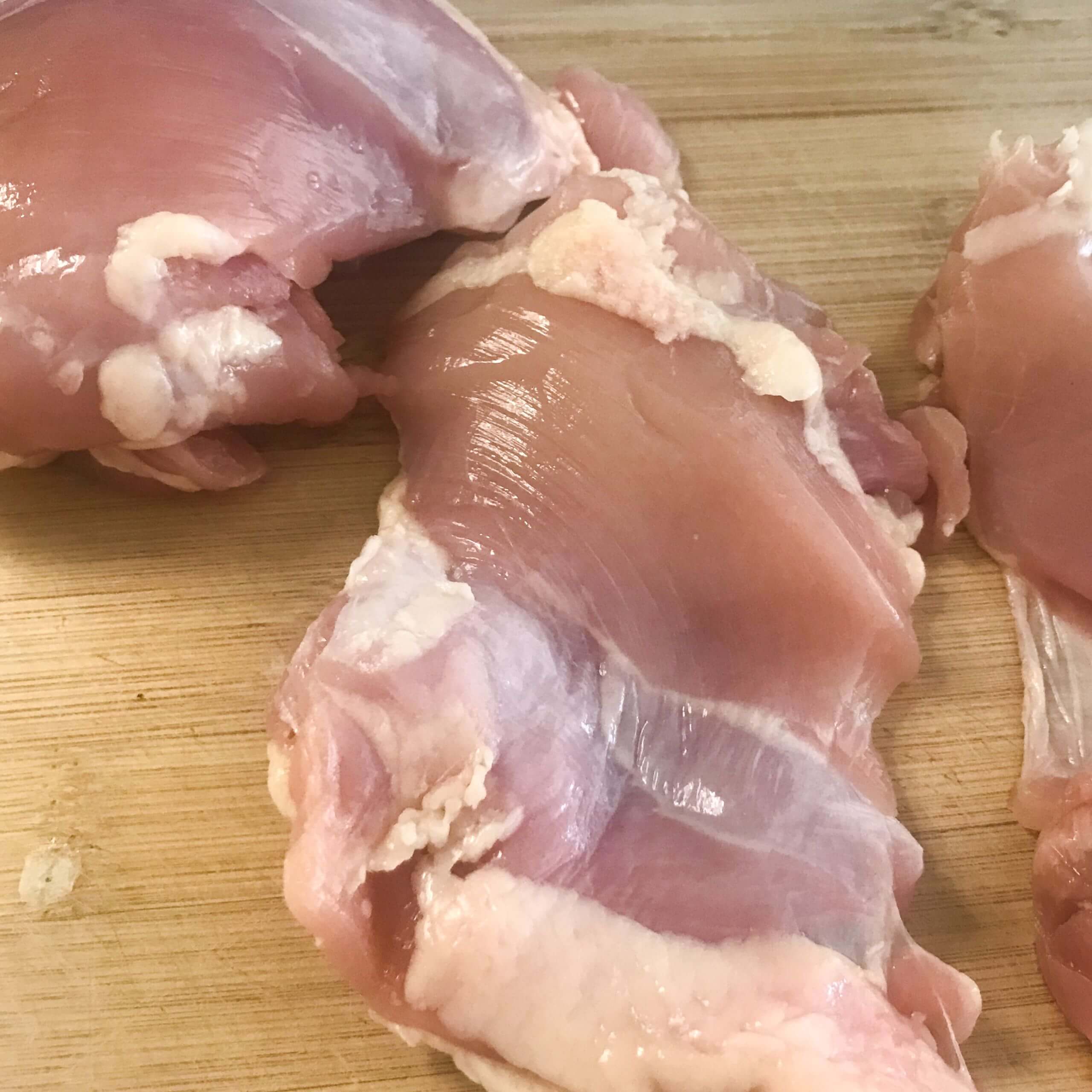 skinned chicken thighs on cutting board