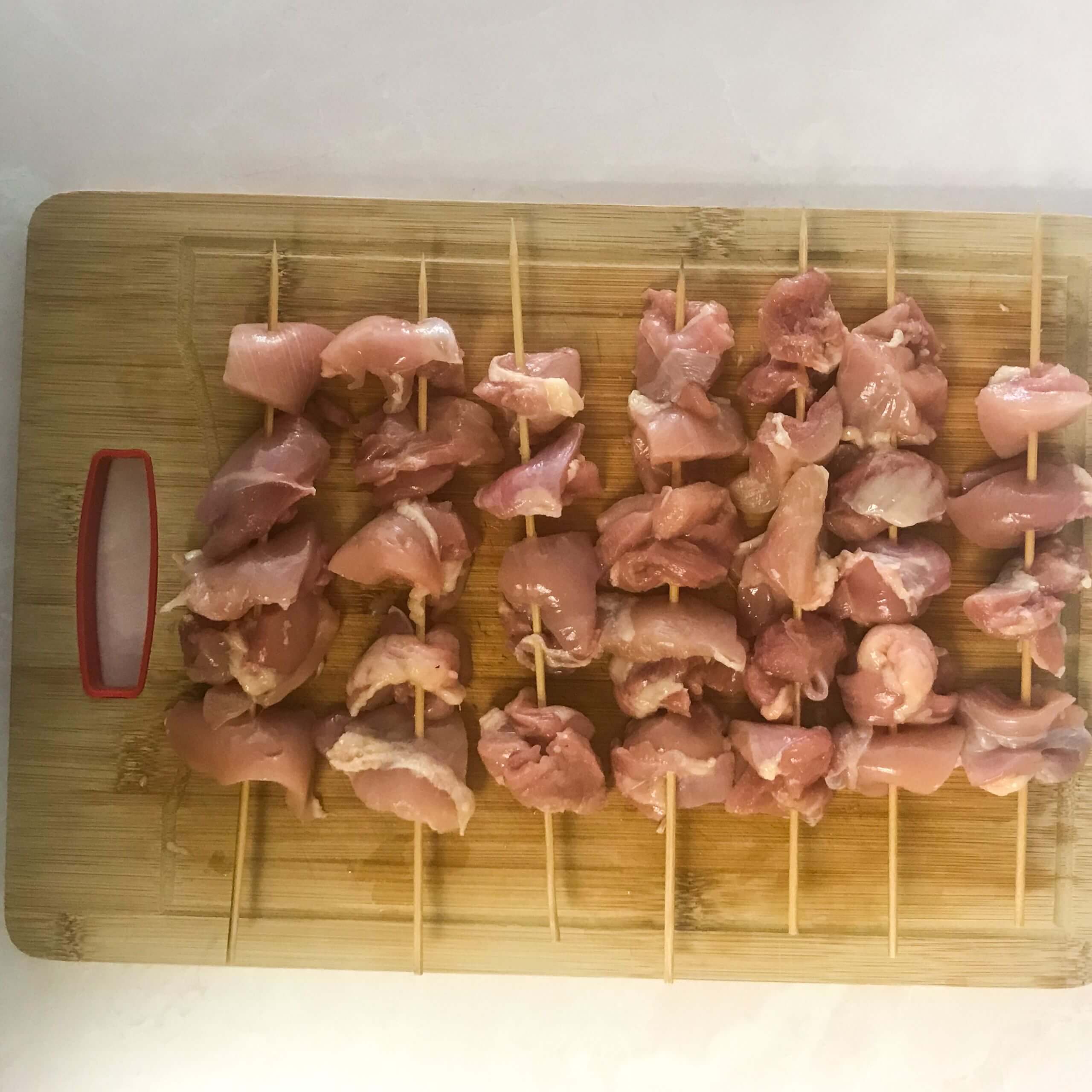 raw chicken skewers on cutting board