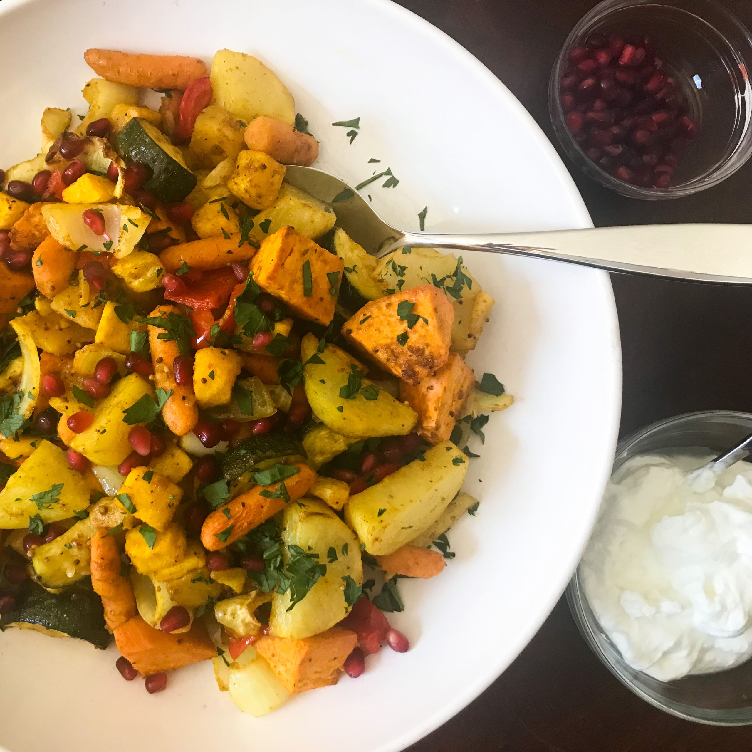 bowl of roasted vadouvan veggies and bowls of yogurt and pomegranate seeds