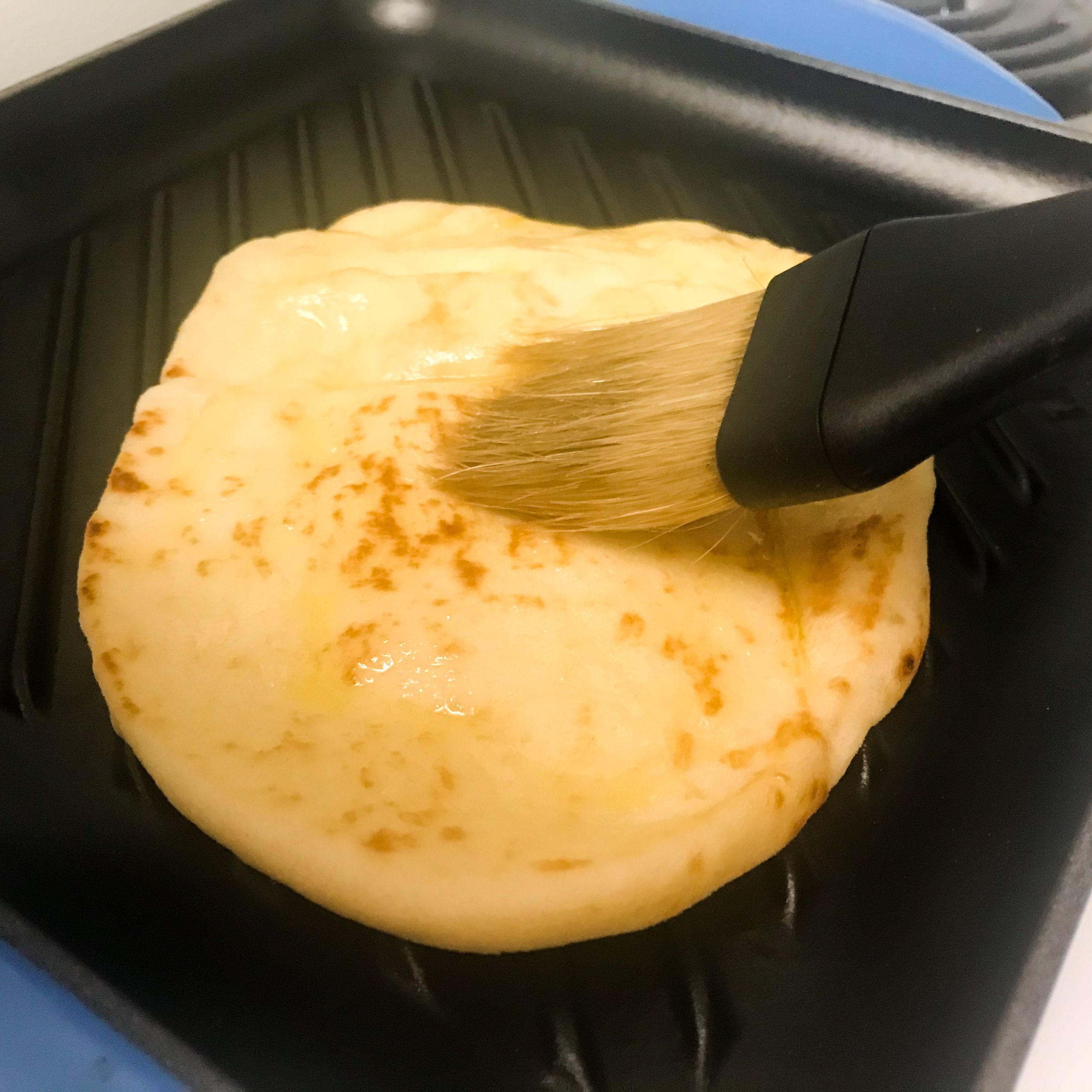 naan bread being brushed with oil