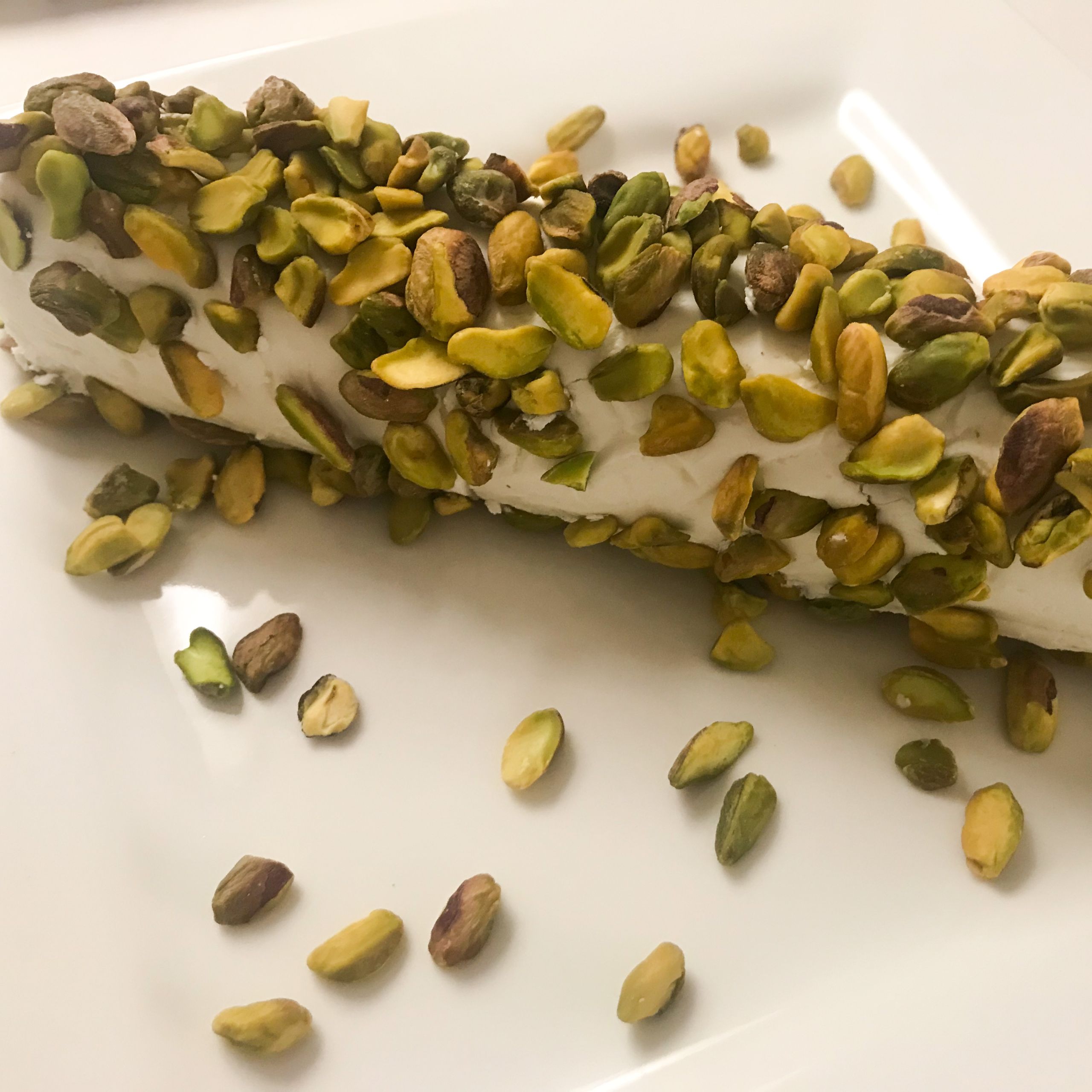log of goat cheese covered in pistachios on a plate