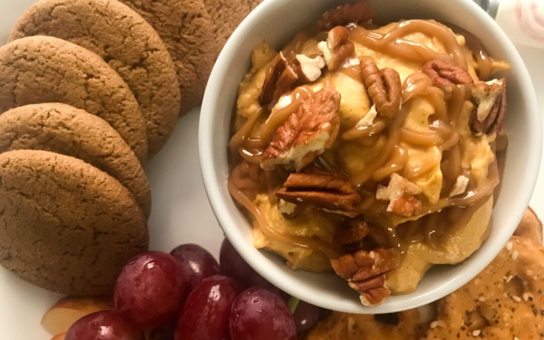 pumpkin caramel dip on platter with cookies, apple slices and pretzels