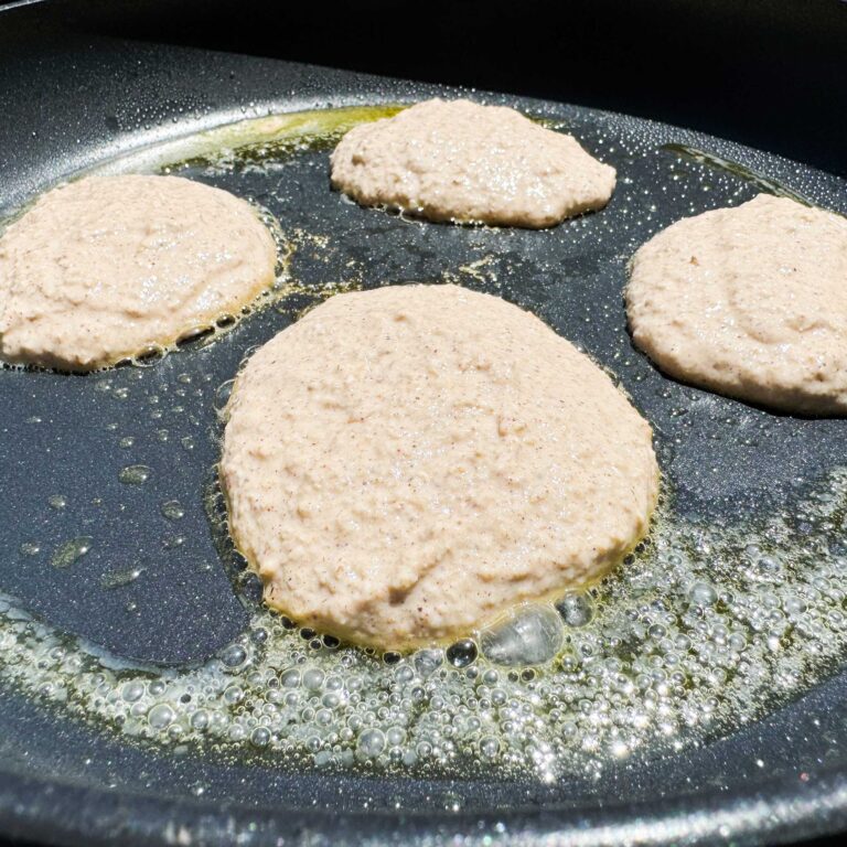 raw pancakes cooking in a skillet.